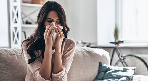 Na zdjęciu przedstawiona jest kobieta z alergią, w danym momencie kicha