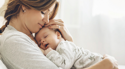 Na zdjęciu przedstawiono kobietę, która przytula niemowlę